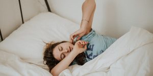 woman covered in white blanket sleeping on white bed comforter